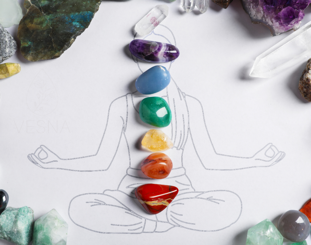 na narysowanej postaci medytującego człowieka ułożone są naturalne kamienie szlachetne odpowiadającego kolorami kolorom poszczególnych czakr