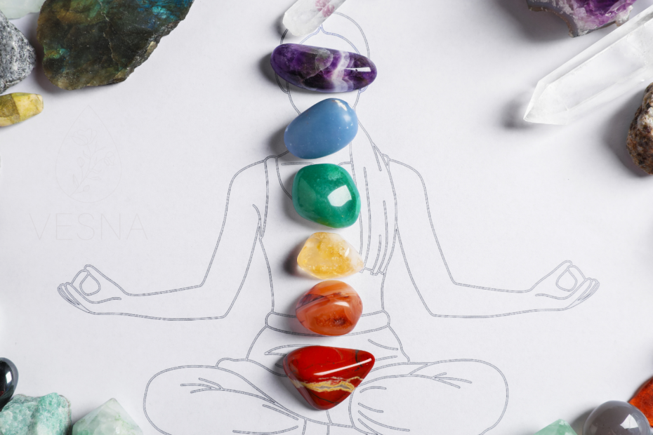 na narysowanej postaci medytującego człowieka ułożone są naturalne kamienie szlachetne odpowiadającego kolorami kolorom poszczególnych czakr